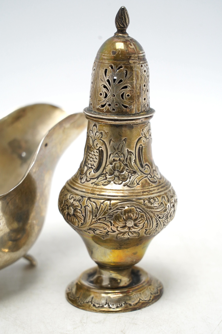 A late Victorian repousse silver pedestal sugar caster, Birmingham, 1893, 14.2cm, together with a later silver sauceboat, 6.6oz. Condition - poor to fair